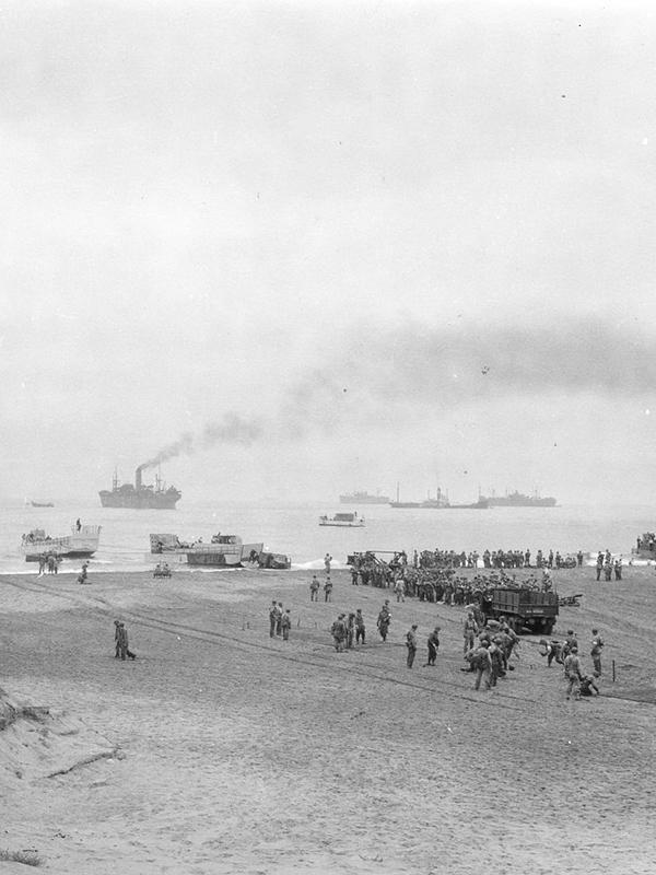 Men unloading landing craft over a sandy beach during Operation Torch, the landings in North Africa.